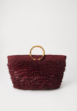 Burgunderfarbene Strohtasche mit strukturiertem Fransen, ausgestattet mit einem Bambushandgriff. Breites, offenes Design für einfachen Zugriff und Stauraum.