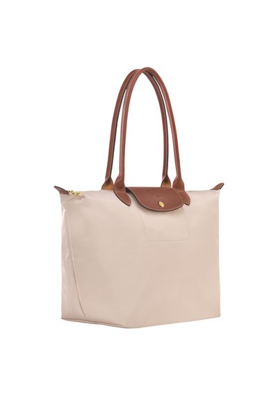 Beige tote bag with brown leather handles, featuring a flap closure and a flat bottom. Smooth texture with a subtle sheen.