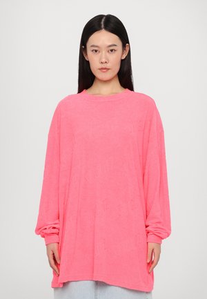 Übergroßer Pullover in leuchtendem Pink, mit strukturiertem Stoff und geprägtem Schriftzug, langen Ärmeln und klassischem Rundhalsausschnitt.