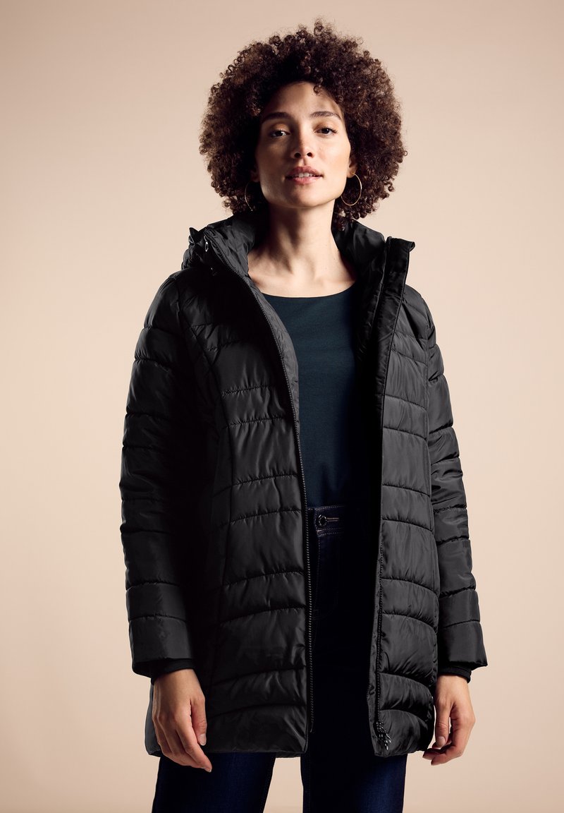 Abrigo negro tipo puffer con patrón acolchado y capucha, que contrasta con una parte superior oscura debajo. Cuenta con una cremallera frontal y bolsillos laterales.
