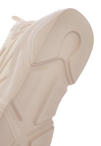Helle beige Sneaker-Sohle mit strukturiertem Muster. Besitzt eine dicke, skulptierte Form und eine glatte Oberfläche mit erhabenen Akzenten.