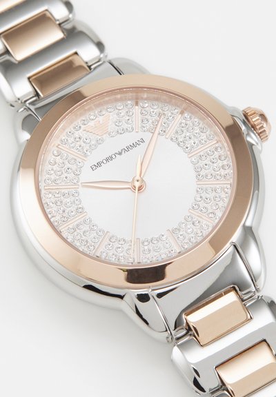 Zegarek na rękę Emporio Armani w srebrnych i różowo-złotych tonacjach, tarcza zdobiona kryształami, trzy wskazówki oraz metalowa bransoleta łączona.