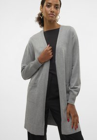 Gray long cardigan made of soft knit fabric, featuring an open front, two side pockets, and ribbed cuffs. Smooth texture, relaxed fit.