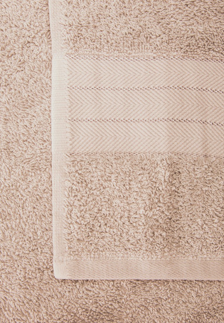 Beige Baumwollhandtuch mit strukturierter Oberfläche. Verfügt über einen glatten Rand mit Fischgrätmuster und dekorativer Stickerei. Weich und saugfähig.