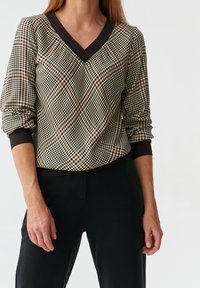 Maglione a V con un motivo a quadri in marrone e beige, con polsini e orlo scuri, realizzato in tessuto leggero.