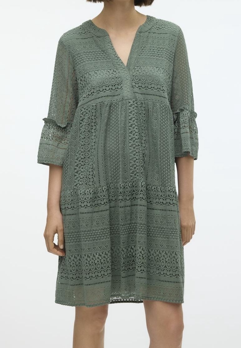 Robe en dentelle verte avec décolleté en V, manches 3/4 et design à volants. Présente des motifs complexes et une coupe décontractée. Texture légère.