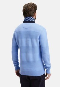 Pull léger bleu avec une texture côtelée et des rayures horizontales. Col boutonné en bleu foncé avec une doublure rayée.