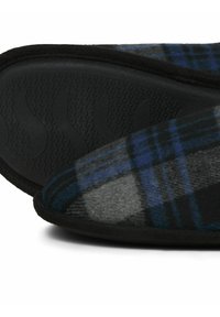 Chaussons en peluche arborant un design à carreaux noir et bleu, avec un dessus doux et une semelle en caoutchouc noir texturé pour une meilleure adhérence.