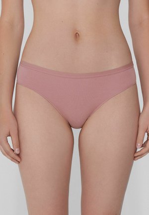 Světlé růžové bikiny s hladkou texturou, nízkým střihem a bez viditelných vzorů či kovových částí, sedící nad boky.