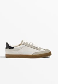 Weiße Sneaker mit grauem Wildlederzehenbereich und schwarzem Fersenelement. Verfügt über weiße Schnürsenkel, eine strukturierte Gummisohle und genähte Akzente an der Seite.