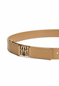 Cintura in pelle color tan con una fibbia geometrica dorata. Texture liscia con cuciture decorative e un'estremità rettangolare per la regolazione.