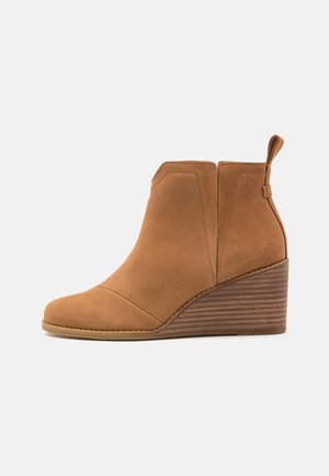Braune Wildleder-Ankle-Boots mit runder Zehe, Keilabsatz und genähten Details. Verfügt über eine Zuglasche und eine glatte Textur.