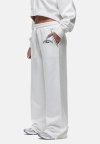 Witte cropped sweatshirt gecombineerd met losse witte sweatpants met een elastische tailleband, zijzakken en groene logo-borduursels.