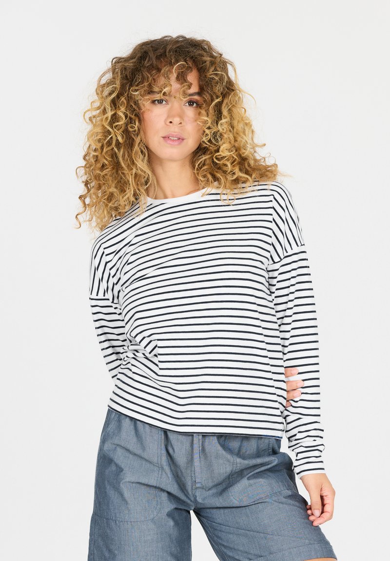Gestreepte longsleeve top in wit en marineblauw. Kenmerkt zich door een relaxte pasvorm, ronde hals en een gestructureerde stof. Gecombineerd met losse blauwe shorts.