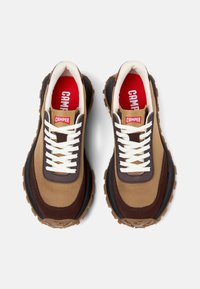 Sneaker marroni e beige con lacci bianchi, suole in gomma e interno rosso. Presentano un colletto imbottito e sovrapposizioni testurizzate distintive.