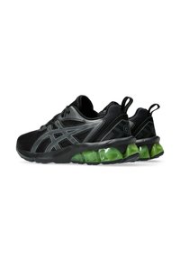 Scarpe da atleta nere con una tomaia in mesh testurizzato. Imbottitura trasparente verde al tallone e accenti neri riflettenti sui lati.