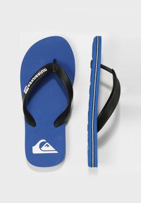 Des tongs en caoutchouc bleu avec des sangles noires, un semelle texturée et un logo blanc. La vue de côté montre une fine bande d'accent blanc le long de la semelle.