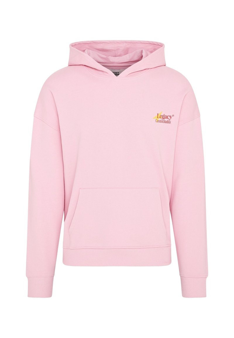Sweat à capuche rose en tissu doux avec une poche avant, des épaules tombantes, et un logo jaune et orange sur le côté supérieur gauche.