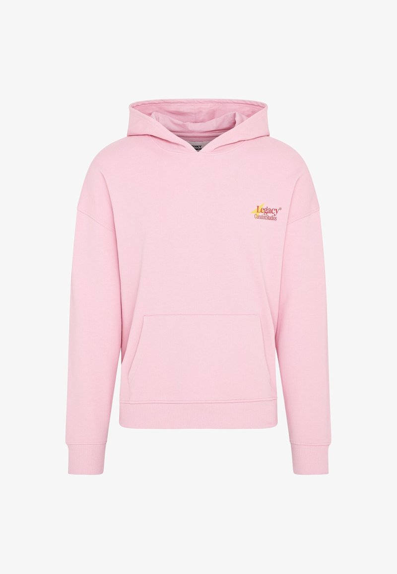 Sweat à capuche rose en tissu doux avec une poche avant, des épaules tombantes, et un logo jaune et orange sur le côté supérieur gauche.
