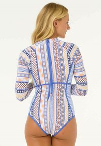 Langærmet svømmedragt med geometriske mønstre i blå, orange og hvid. Har en lynlås lukning bagpå og en tætsiddende pasform.