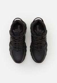 Les baskets noires présentent une tige en cuir lisse, un bout rond, une épaisse semelle en caoutchouc et une couture complexe. Les lacets sont passés dans des œillets pour un ajustement parfait.