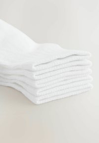 Chaussettes en coton blanc empilées horizontalement, affichant une texture douce et un design simple et sans couture. Aucun motif ni accent visible.