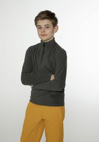 Pullover in felpa grigio scuro con colletto alto e zip a metà, abbinato a pantaloni gialli. Tessuto morbido e vestibilità casual.