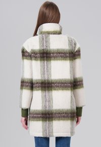 White wool blend coat with green and brown check pattern, drop shoulders, and a high collar. Soft, textured fabric with a relaxed fit.