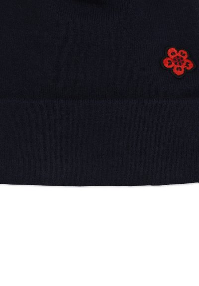 Bonnet en maille bleu marine avec un ourlet retroussé, orné d'une fleur rouge brodée sur le devant. Texture douce et forme ajustée.