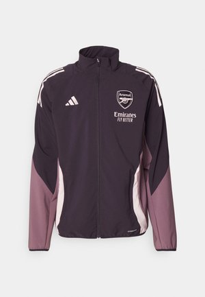 Giacca Adidas viola con colletto alto, zip completa, accenti bianchi e logo dell'Arsenal. Presenta un tessuto leggero e pannelli laterali a contrasto.