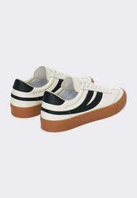 Sneakers bianchi con strisce nere, suole in gomma e dettagli in pelle testurizzata. Presentano un design a collarino basso e lacci rotondi.