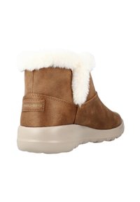 Brown suede ankle boot with a white fur cuff, featuring a beige rubber sole and a subtle Skechers logo on the back.