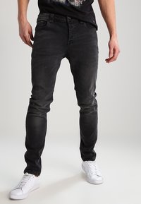 Slim-fit svarta denimjeans med en blekt struktur, femfickorsdesign, förstärkt sömnad och en lätt stretch för komfort.