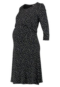 Czarna sukienka ciążowa w białe i fioletowe wzory serc, z rękawami 3/4 i cienkim czarnym paskiem zawiązanym na brzuchu.