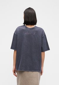 Μπλε τζιν T-shirt σε μεγάλο μέγεθος με κοντά μανίκια, διακοσμημένο με κεντημένο λογότυπο στο πίσω μέρος, υφασμένο ύφασμα και κλασική στρογγυλή λαιμόκοψη.