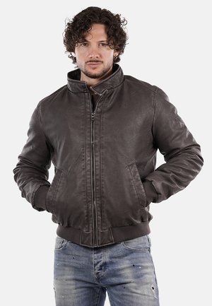 Giubbotto bomber in pelle marrone con chiusura a zip, polsini e colletto a coste. Il materiale ha una texture liscia ed è leggermente invecchiato.