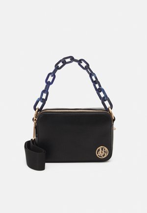 Sac à main noir avec une fermeture éclair dorée, détail de logo et surface texturée. Il dispose d'une chaîne de bandoulière aux tons bleus et d'une bandoulière amovible.