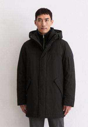 Schwarze Parkajacke mit Reißverschluss, verstellbarem Kapuzenkragen, Seitentaschen und strukturiertem Stoff. Enthält ein Abzeichen am linken Ärmel.