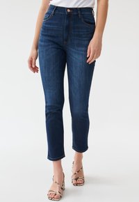 High-waisted dark blue jeans with a slim fit, featuring front pockets, a classic button closure, and a smooth denim texture.