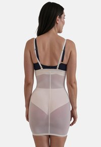 Abito modellante beige con spalline regolabili, orlo in pizzo e design senza cuciture. Presenta una texture trasparente e una silhouette aderente.