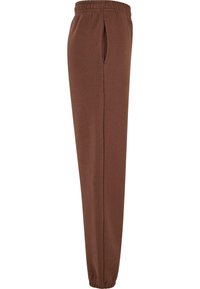 Bruine joggingschoenen van zachte stof, met een elastische tailleband, zijzakken en taps toelopende boorden bij de enkels.