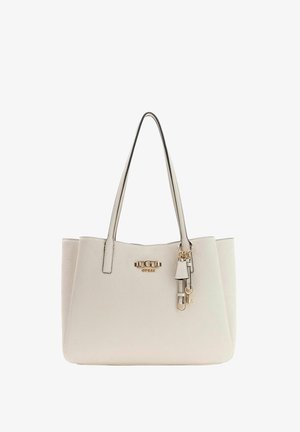 Borsa tote Guess color crema con doppi manici, motivo logo impresso e ciondoli decorativi in tono oro appesi vicino al bordo superiore.