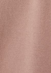 Strickstoff in zartem Blush-Pink, mit einer strukturierten, leicht dehnbaren Oberflächenmusterung und gleichmäßig verteilten Schlaufen.