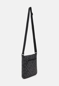 Borsa a tracolla nera con motivo a scacchi, dotata di tasca frontale con zip, tracolla regolabile e superficie liscia. Presenta dettagli del logo discreti.