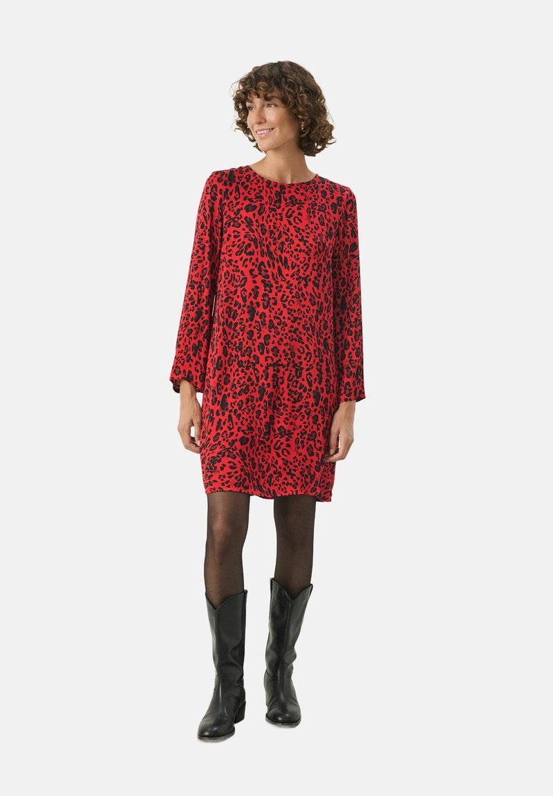 Rød kjole med sort leopardprint, lange ærmer, rund halsudskæring, knælang, parret med sorte knæhøje støvler og gennemsigtige sorte strømpebukser.