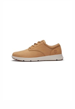 Zapatilla de cuero marrón con perfil bajo, punta redonda y diseño con cordones. Presenta una suela de goma blanca con patrones de relieve y logo en relieve.