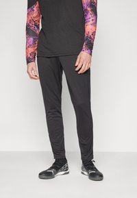 Black athletic pants made of lightweight fabric, featuring a slim fit. Paired with a long-sleeve multicolored top and black sports shoes.