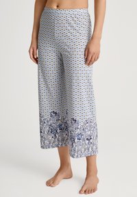 Lichte, vloeiende blauw-witte geprinte broek met bloemaccenten en een herhalend strikpatroon. Wijde pijpen en een lengte tot halverwege de kuit.