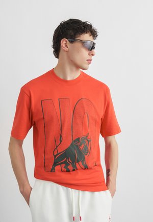 Ung mand iført orange T-shirt med stort 