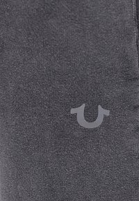 Grijze stoffen legging met een gladde textuur, voorzien van een klein, lichtgrijs logo. Het ontwerp is slim fit met stikseldetails.